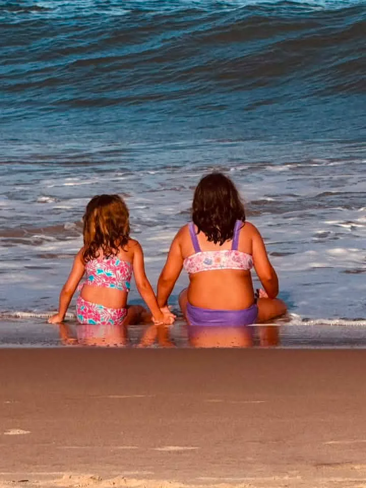 two girls sitting on the ocean city md beach
